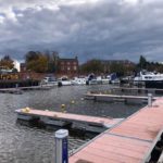 Booms and service bollards with motor boats and house in background