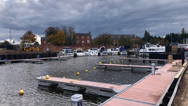 Booms and service bollards with motor boats and house in background