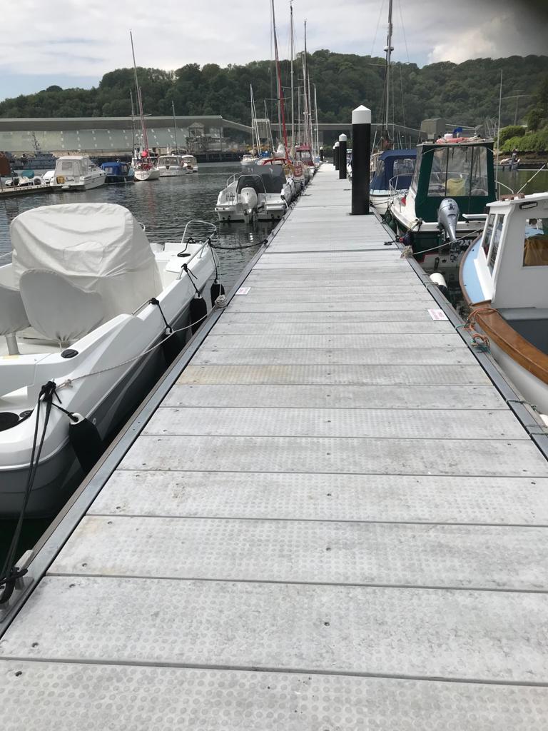 Grey GRC decked pontoon with two motorboats moored, one either side
