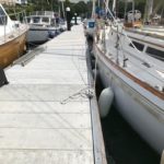 Grey GRC decked pontoon with a sailing boat and a motorboat moored, one either side