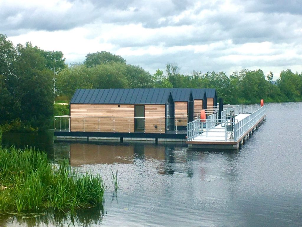 Small individual houseboats floating in a row along a pontoon walkway