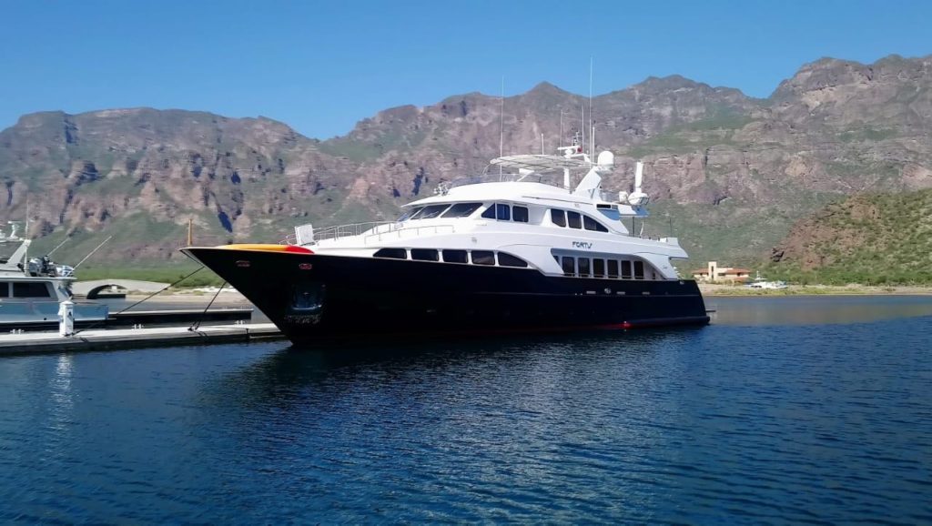 Superyacht moored alongside concrete breakwater with moutons in the background