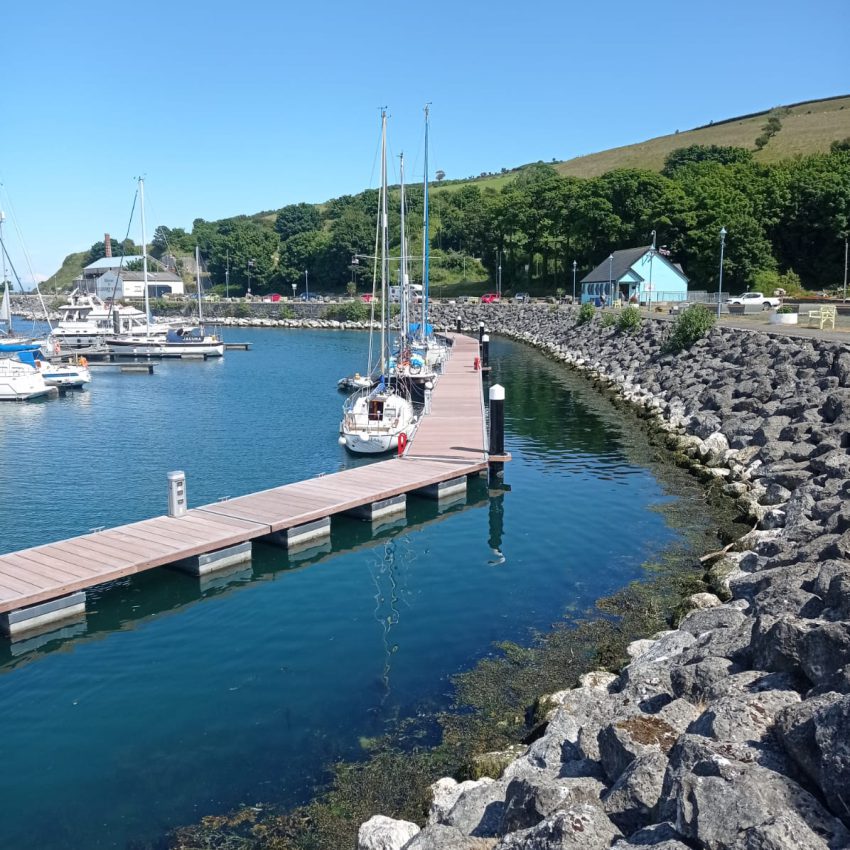 Terrecotta coloured marina pontoon following the curve of the breakwater