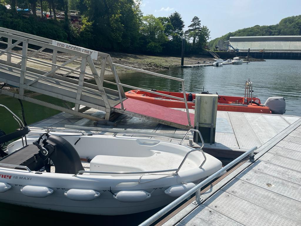 Grey pontoons with two small boats alongside
