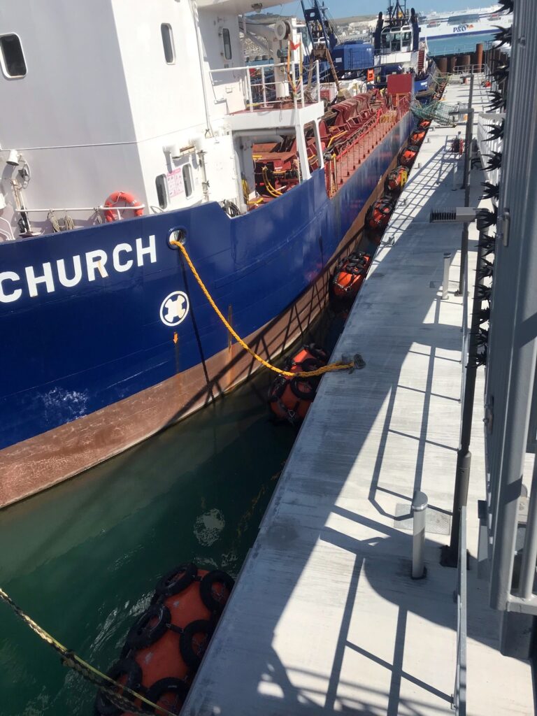 Tug boat moored alongside floating concrete pontoon