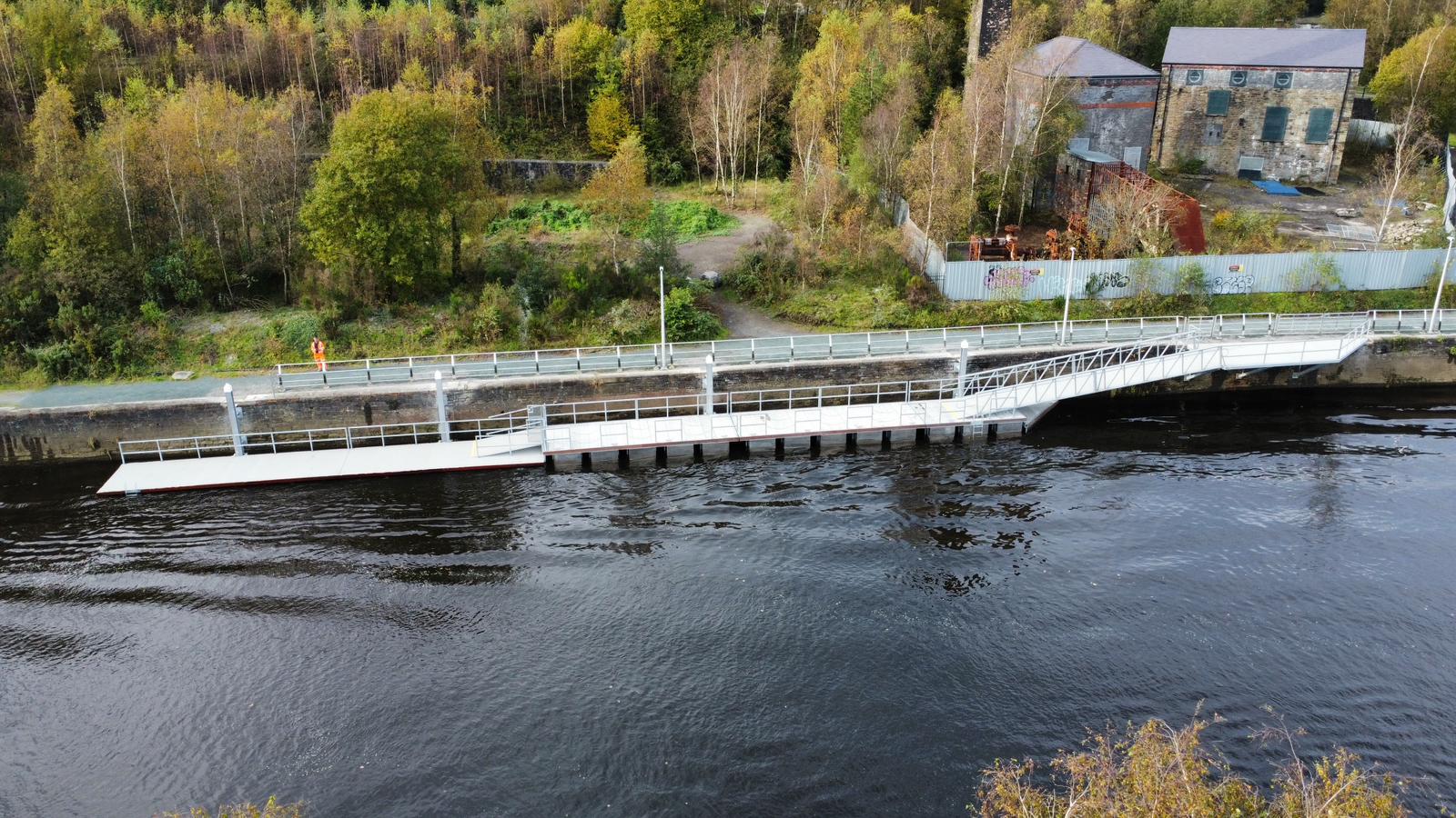 Bridge pontoon on river's edge with greenery in the background